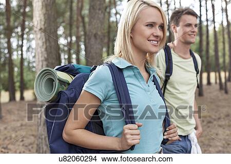 Beautiful young backpacker with man trekking in forest View Large Photo Image Picture - Beautiful young backpacker with man trekking in forest. Fotosearch