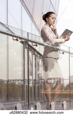Beautiful young businesswoman using digital tablet at office railing View Large Photo Image Stock Image - Beautiful young businesswoman using digital tablet at office railing. Fotosearch