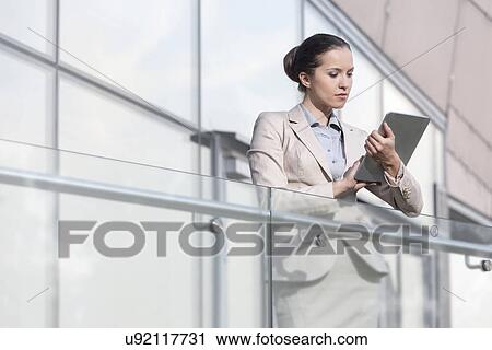 Beautiful young businesswoman using digital tablet at office railing View Large Photo Image Stock Image - Beautiful young businesswoman using digital tablet at office railing. Fotosearch