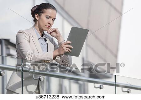 Beautiful young businesswoman using digital tablet at office railing View Large Photo Image Stock Photo - Beautiful young businesswoman using digital tablet at office railing. Fotosearch