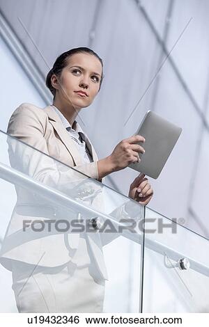 Beautiful young businesswoman using digital tablet at office railing View Large Photo Image Stock Photograph - Beautiful young businesswoman using digital tablet at office railing. Fotosearch