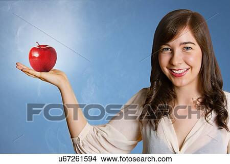 Picture - Beautiful young woman holding red apple. Fotosearch