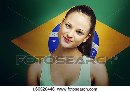 Stock Photograph - Beautiful Young woman smiling standing in front of Brazilian flag. Fotosearch