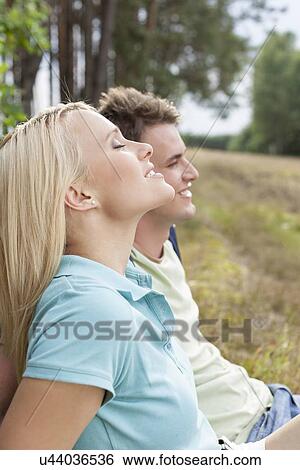 Beautiful young woman with eyes closed relaxing by man in forest View Large Photo Image Stock Photograph - Beautiful young woman with eyes closed relaxing by man in forest. Fotosearch