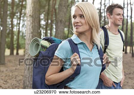 Stock Image - Beautiful young woman with man trekking in forest. Fotosearch
