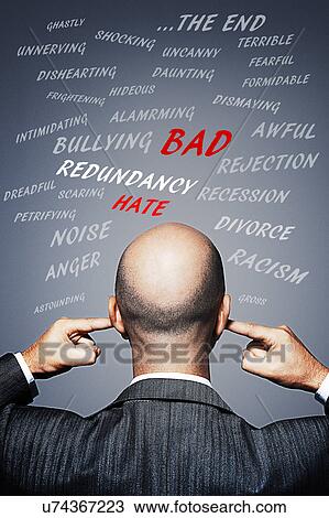 Stock Image - Businessman plugging his ears to avoid negative words and energy. Fotosearch