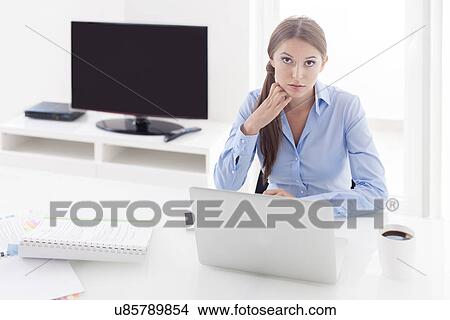 Businesswoman looking bored in front of laptop and television View Large Photo Image Picture - Businesswoman looking bored in front of laptop and television. Fotosearch