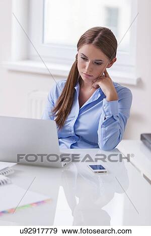 Businesswoman looking bored in front of laptop View Large Photo Image Stock Photo - Businesswoman looking bored in front of laptop. Fotosearch