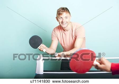 Stock Image - Caucasian man playing table tennis with friend. Fotosearch