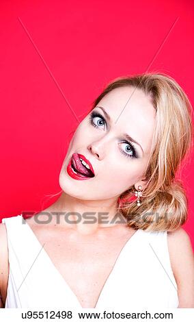 Stock Photo - Caucasian woman wearing white dress on red background licking her lips. Fotosearch