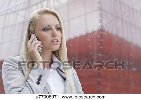 Close-up of blond businesswoman conversing on mobile phone with office building in background View Large Photo Image Stock Image - Close-up of blond businesswoman conversing on mobile phone with office building in background. Fotosearch