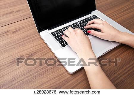 Stock Photograph - Close-up of businesswoman's hands using laptop at table. Fotosearch