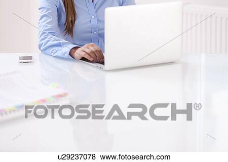 Stock Photo - Close-up view of beautiful woman using laptop at desk. Fotosearch