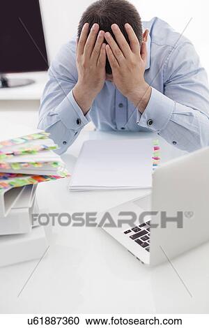 Close-up view of Caucasian businessman with heads in hands at his desk View Large Photo Image Stock Image - Close-up view of Caucasian businessman with heads in hands at his desk. Fotosearch
