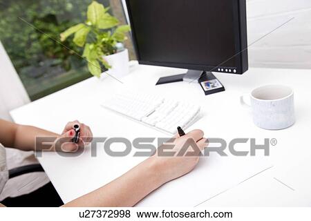 Cropped image of businesswoman noting on paper at computer desk View Large Photo Image Stock Photo - Cropped image of businesswoman noting on paper at computer desk. Fotosearch