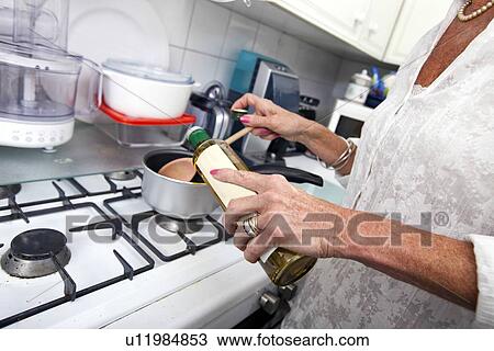 Cropped image of senior woman adding olive oil to saucepan at kitchen counter View Large Photo Image Stock Image - Cropped image of senior woman adding olive oil to saucepan at kitchen counter. Fotosearch