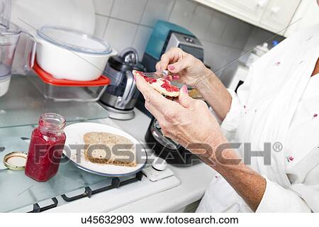Cropped image of senior woman applying jam on toast in kitchen View Large Photo Image Stock Image - Cropped image of senior woman applying jam on toast in kitchen. Fotosearch