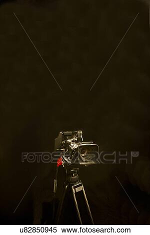 Stock Photography - Digital camera and tripod against black background. Fotosearch