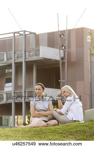 Stock Photo - Displeased young businesswomen sitting on office lawn. Fotosearch
