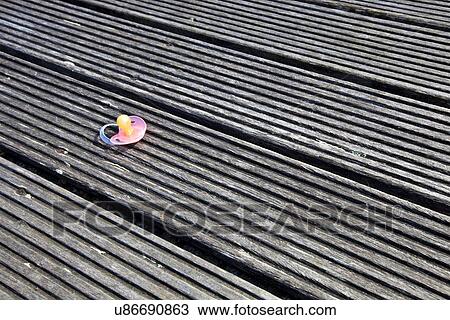 Stock Image - Dropped pacifier on wooden flooring. Fotosearch
