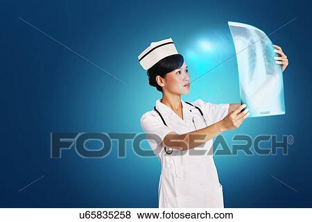 Female doctor analyzing x-ray report over blue background View Large Photo Image Stock Photo - Female doctor analyzing x-ray report over blue background. Fotosearch