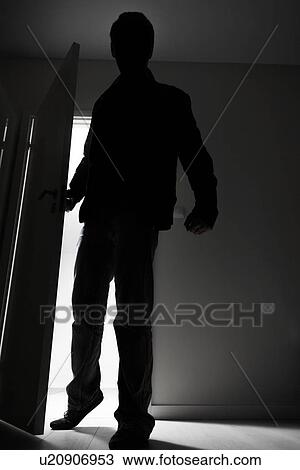 Stock Image - Full-length of burglar breaking into house. Fotosearch