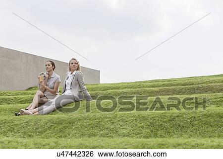 Full length of female business executives sitting on grass steps against sky View Large Photo Image Stock Photograph - Full length of female business executives sitting on grass steps against sky. Fotosearch