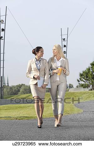 Full length of happy young businesswomen with disposable cup and laptop walking on street View Large Photo Image Stock Photography - Full length of happy young businesswomen with disposable cup and laptop walking on street. Fotosearch