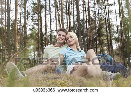 Full length of romantic young hiking couple relaxing in forest View Large Photo Image Stock Photograph - Full length of romantic young hiking couple relaxing in forest. Fotosearch