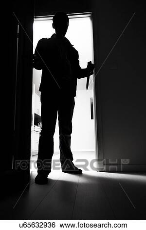 Stock Photograph - Full-length of thief with knife entering into dark room. Fotosearch