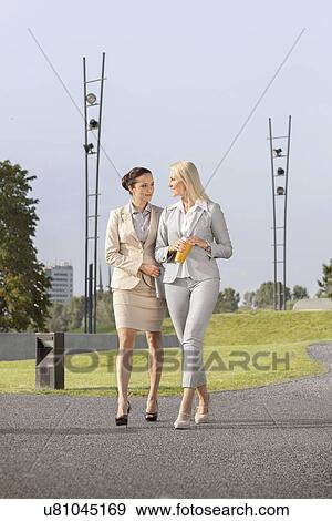 Full length of young businesswomen with disposable cup and laptop walking on street View Large Photo Image Stock Photo - Full length of young businesswomen with disposable cup and laptop walking on street. Fotosearch