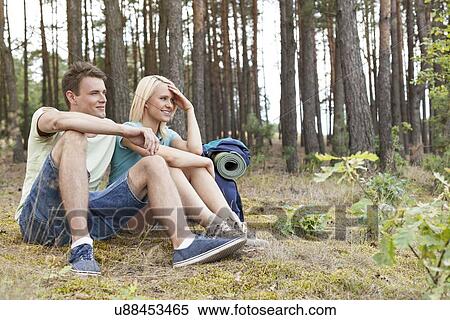 Full length of young hiking couple relaxing in woods View Large Photo Image Stock Photography - Full length of young hiking couple relaxing in woods. Fotosearch