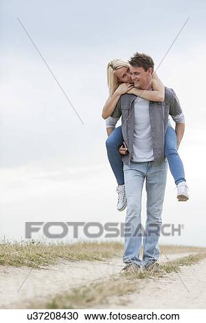 Full length of young man giving piggyback ride to woman on trail at field View Large Photo Image Stock Image - Full length of young man giving piggyback ride to woman on trail at field. Fotosearch