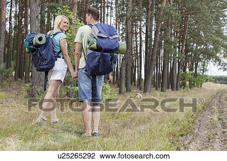 Full length rear view of young hiking couple holding hands in countryside View Large Photo Image Stock Image - Full length rear view of young hiking couple holding hands in countryside. Fotosearch