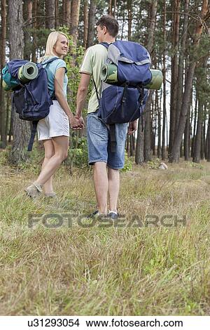 Full length rear view of young backpackers holding hands in countryside View Large Photo Image Picture - Full length rear view of young backpackers holding hands in countryside. Fotosearch