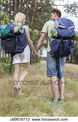Full length rear view of young backpackers holding hands in countryside View Large Photo Image Stock Image - Full length rear view of young backpackers holding hands in countryside. Fotosearch