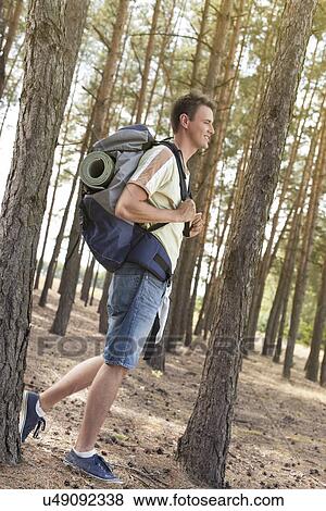 Full length side view of male hiker with backpack walking in forest View Large Photo Image Stock Photo - Full length side view of male hiker with backpack walking in forest. Fotosearch