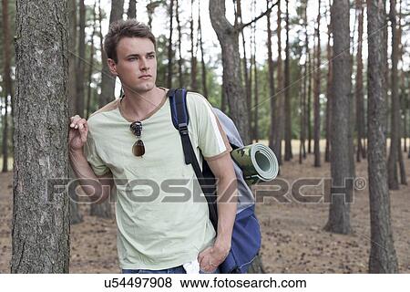 Handsome young man with backpack hiking in woods View Large Photo Image Stock Photo - Handsome young man with backpack hiking in woods. Fotosearch