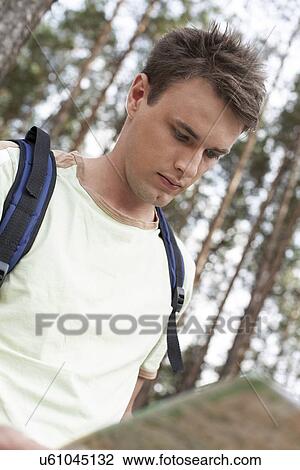 Handsome young man with backpack reading map in forest View Large Photo Image Stock Image - Handsome young man with backpack reading map in forest. Fotosearch