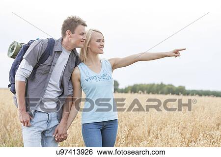 Happy female hiker showing something to man on field against clear sky View Large Photo Image Stock Photograph - Happy female hiker showing something to man on field against clear sky. Fotosearch