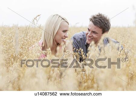 Happy man looking at woman while relaxing amidst field View Large Photo Image Stock Image - Happy man looking at woman while relaxing amidst field. Fotosearch