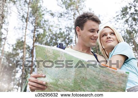 Happy young backpackers holding map in forest View Large Photo Image Stock Image - Happy young backpackers holding map in forest. Fotosearch