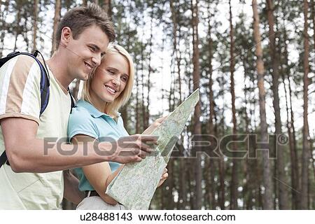 Happy young backpackers looking at map in woods View Large Photo Image Stock Image - Happy young backpackers looking at map in woods. Fotosearch