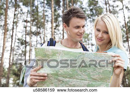 Happy young backpackers reading map in forest View Large Photo Image Stock Photo - Happy young backpackers reading map in forest. Fotosearch