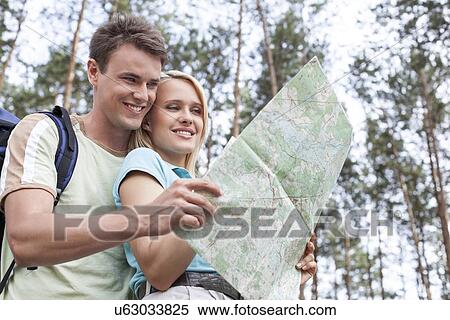 Happy young backpackers reading map in forest View Large Photo Image Stock Photography - Happy young backpackers reading map in forest. Fotosearch