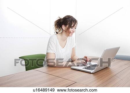 Happy young businesswoman using laptop at table View Large Photo Image Stock Photo - Happy young businesswoman using laptop at table. Fotosearch