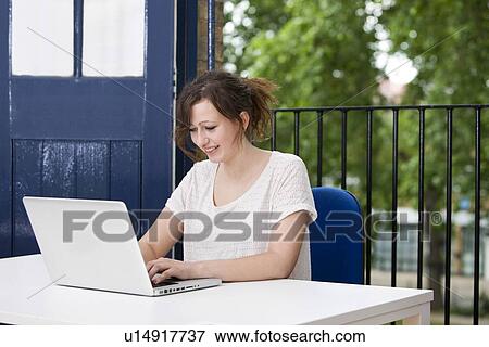Stock Photo - Happy young businesswoman working on laptop at desk. Fotosearch