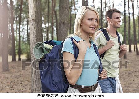 Stock Photography - Happy young female backpacker with man hiking in woods. Fotosearch