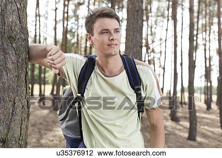 Happy young man with backpack hiking in woods View Large Photo Image Stock Image - Happy young man with backpack hiking in woods. Fotosearch