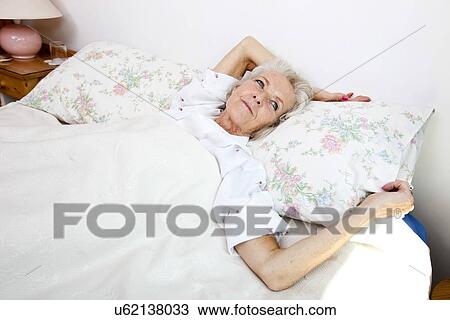 High angle view of senior woman looking away while lying in bed at home View Large Photo Image Stock Image - High angle view of senior woman looking away while lying in bed at home. Fotosearch